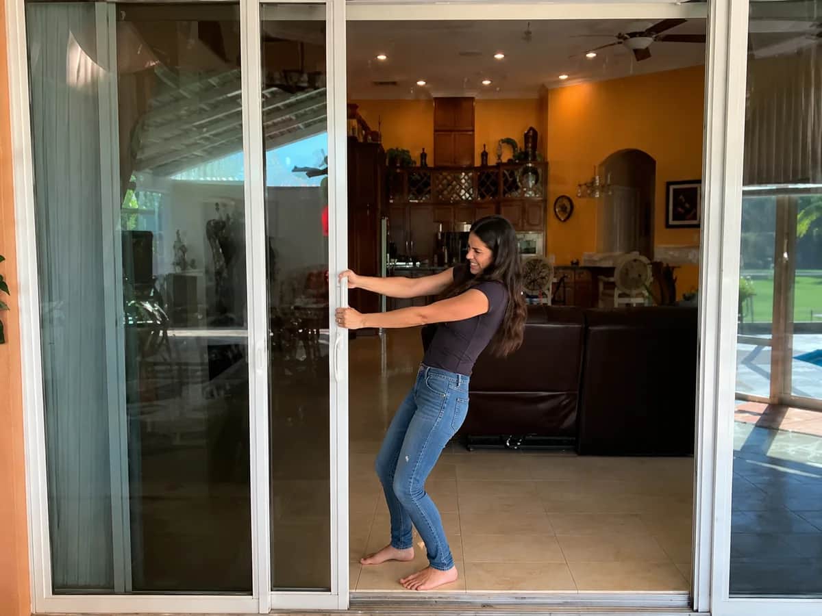 A homeowner hauling a stiff sliding door open with both hands